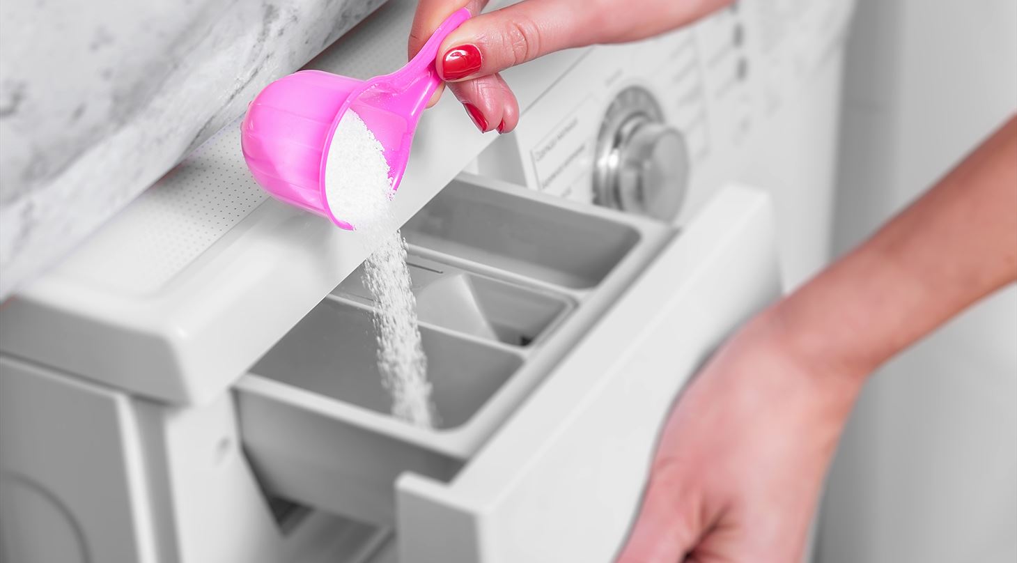 Vaskepulver hældes i vaskemaskine